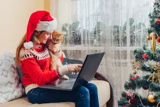 Lady sitting alone and wearing Christmas hat and jumper while holding her cat