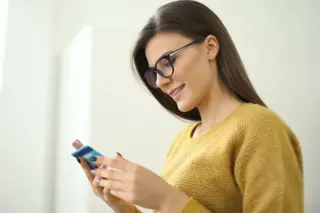 Brunette woman, wearing glasses on her phone with her credit card in card