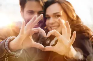 Smiling couple making heart shape with their hands