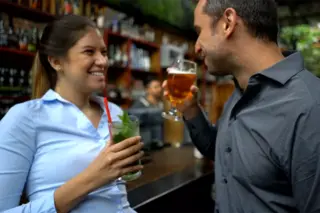 Smiling couple leaning on a bar with drinks