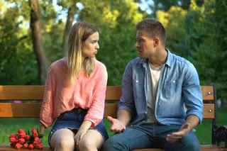 Girl and guy sitting on a park bench, girl angry and breaking up with him