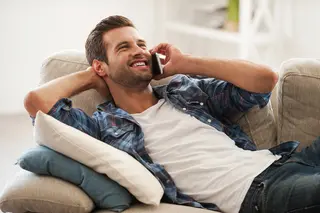 Smiling man lying on the couch talking on the phone