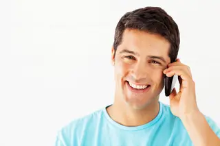 Woman sitting in cafe laughing whilst talking on mobile phone