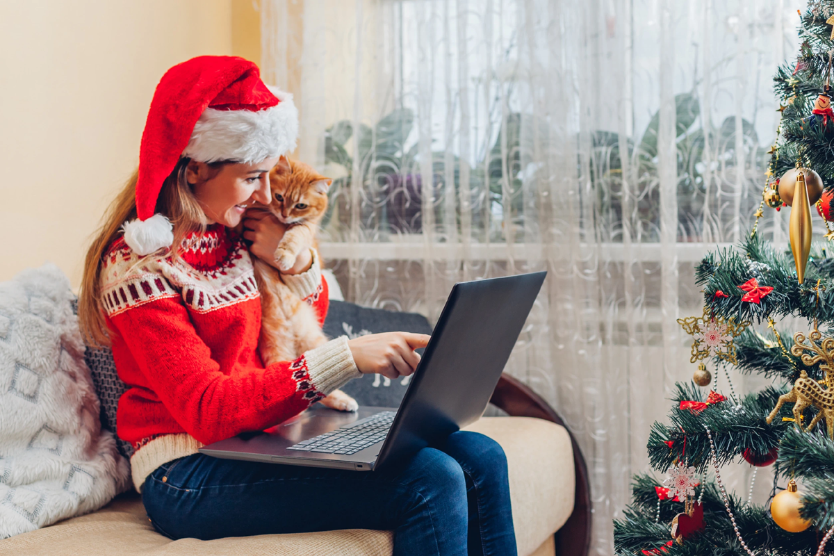 Lady sitting alone and wearing Christmas hat and jumper while holding her cat
