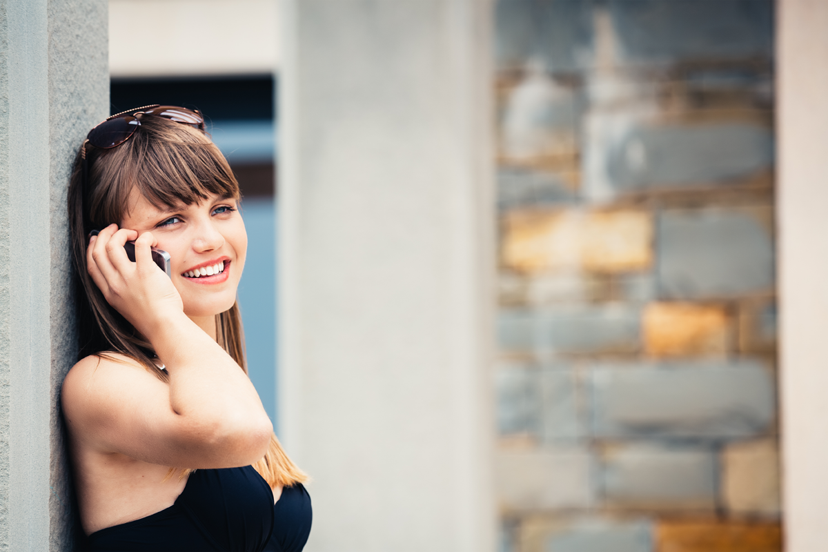 Attractive woman chatting on the phone leaning against a wall