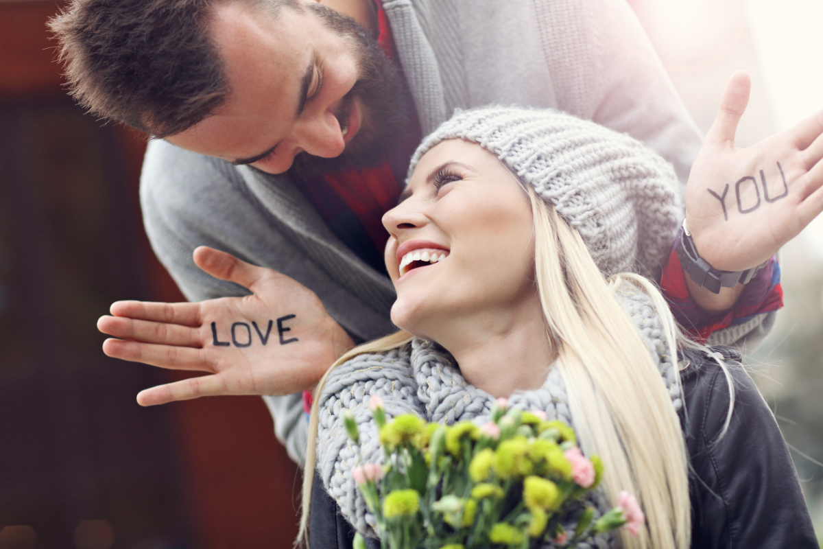 Man with love you written on his hands surprising his girlfriend