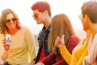 Young group of friends with a cell phone with a chat2date dating profile on screen